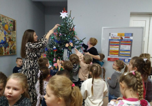 Dzieci wraz z p. Dyrektor ubierają drzewko.