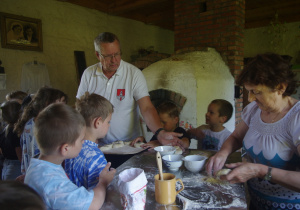 Dzieci przygotowują ciasto do wypieku bułek.