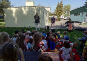 Dzieci słuchają koncertu w wykonaniu muzyków.